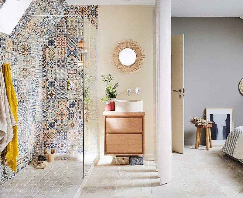 Carreau de ciment multicouleur motifs variés 30x30 cm dans une salle de bain beige avec meuble en bois clair et accents déco naturels
