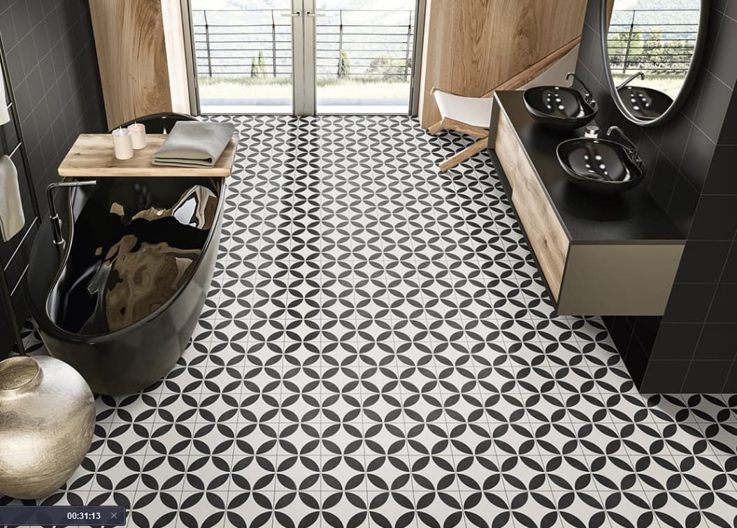 Carreau de ciment noir et blanc motifs géométriques 20x20 cm dans une salle de bain moderne murs gris et bois vasque noire et baignoire autoportante