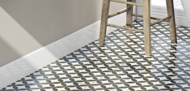Carreau de ciment noir motifs géométriques 20x20 cm dans une cuisine aux murs blancs avec chaise en bois