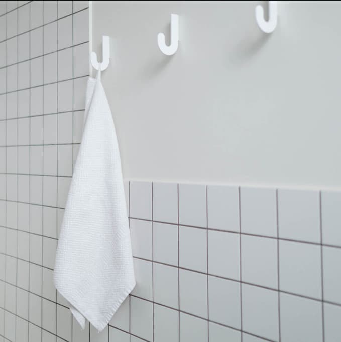 Carrelage uni blanc 10x10 cm dans une salle de bain épurée avec murs blancs, serviette accrochée et détails minimalistes