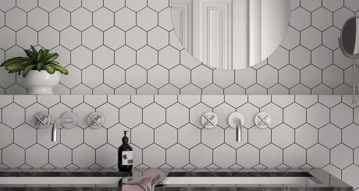 Carreau de ciment blanc hexagonal sur mur salle de bain contemporaine grise avec miroir rond et plantes