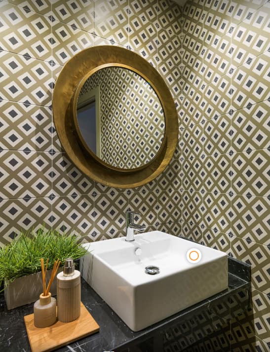 Carreau de ciment or et crème motifs géométriques 20x20 cm dans une salle de bain tendance noire accessoires en bois et miroir rond
