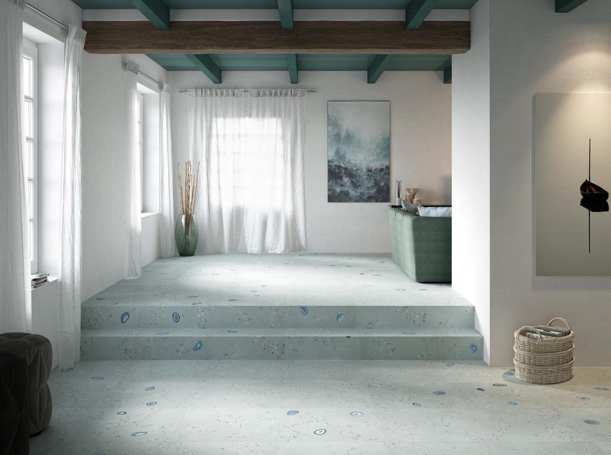 Carrelage pierre vert clair avec incrustations bleues 50x100 cm dans un salon aux murs blancs et canapé taupe, sous toit en bois teinté