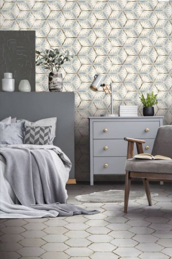 Carreau de ciment blanc géométrique sur sol de chambre grise, lit confortable, commode, plantes, décoration épurée