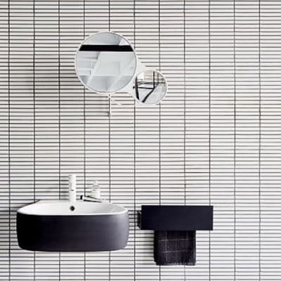 Carrelage uni noir et blanc ligné sans motifs sur une salle de bain épurée avec lavabo noir et miroir rond