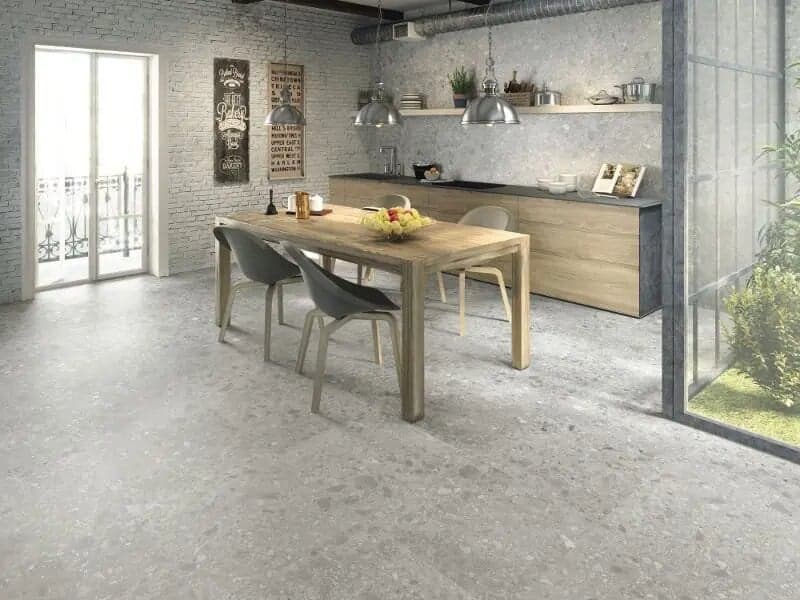 Carrelage effet pierre gris nuancé 80x80 cm dans une cuisine moderne blanc et bois avec table, chaises et éléments décoratifs