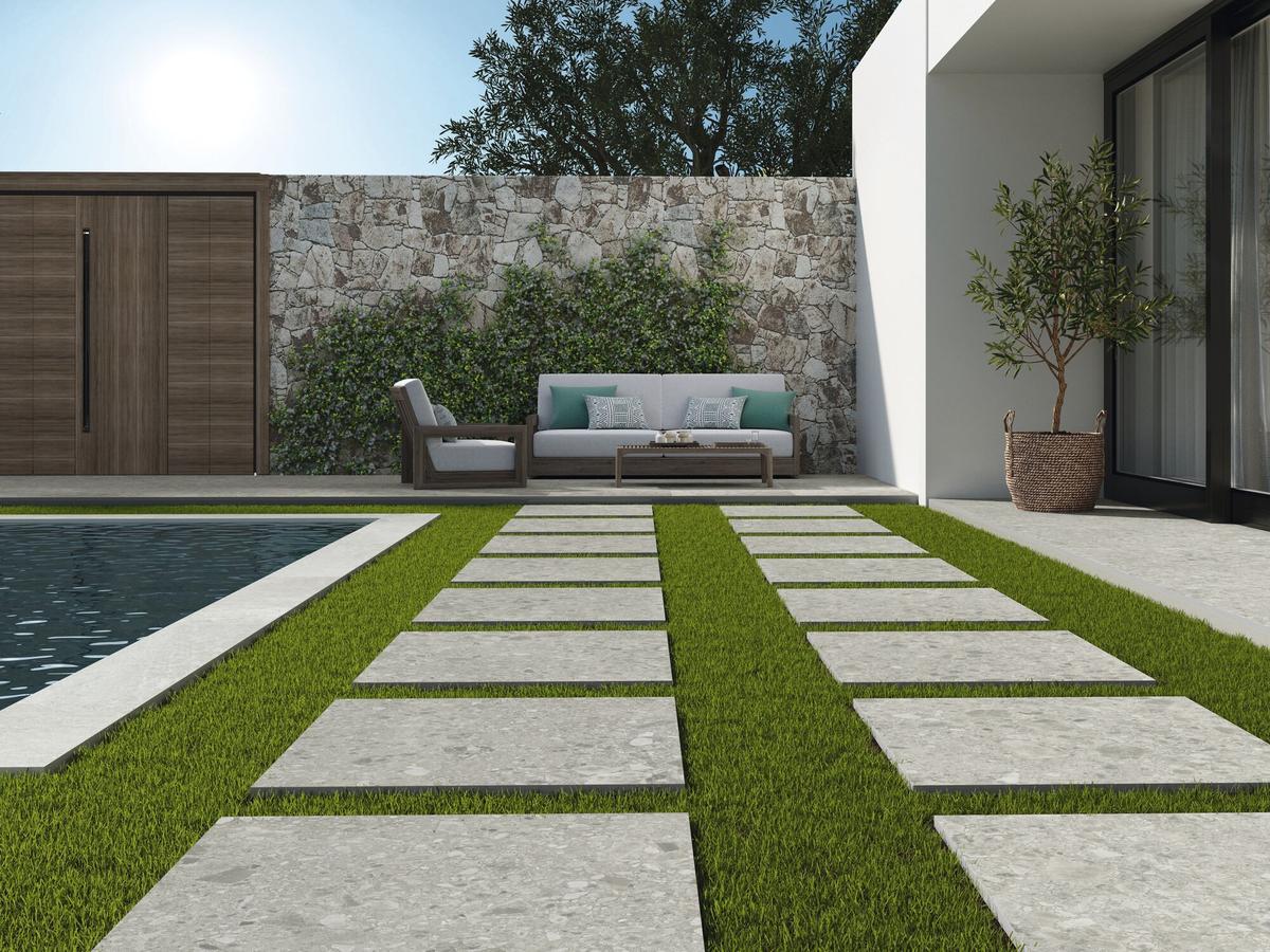 Carrelage Terrazzo gris clair 60x60 cm dans jardin avec pelouse verte, bord de piscine et mobilier dextérieur taupe