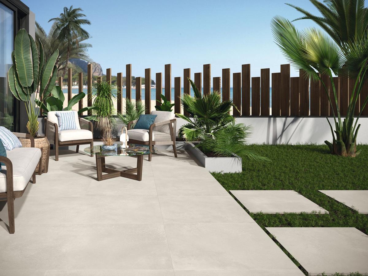 Carrelage effet béton beige lisse 60x60 cm dans une terrasse extérieure vert et bois avec mobilier lounge et plantes