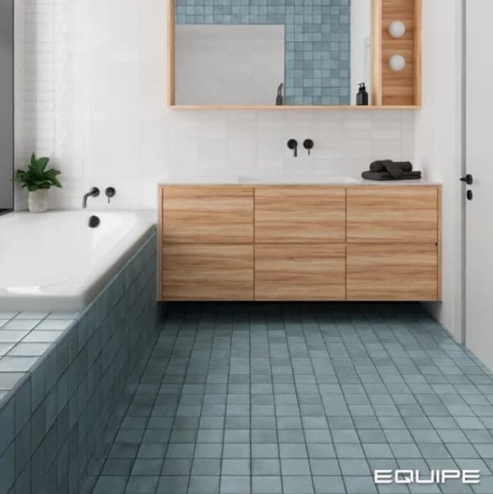 Zellige bleu uni 10x10 cm dans une salle de bain aux murs blancs, meuble en bois, sanitaires blancs