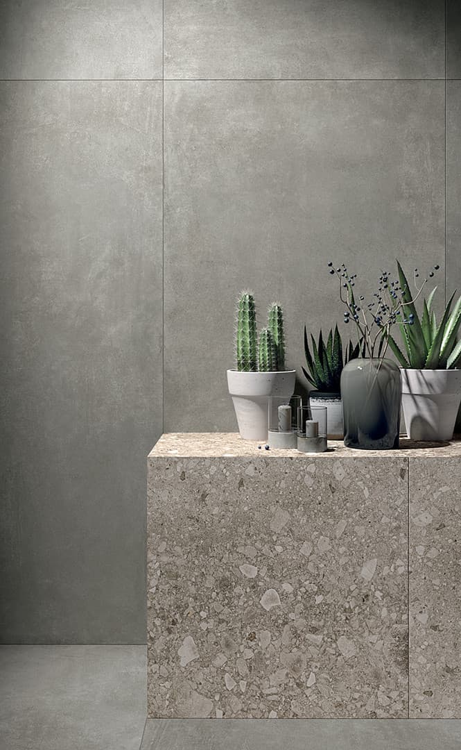 Carrelage effet pierre gris nuancé uni 60x60 cm sur un mur avec comptoir en pierre naturelle et plantes vertes