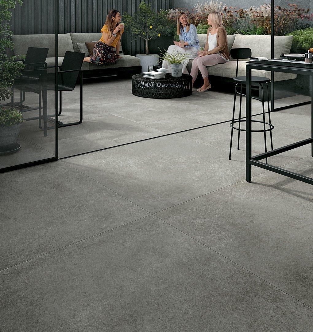 Carrelage effet pierre gris uniforme 60x60 cm sur terrasse avec mobilier moderne et plantes