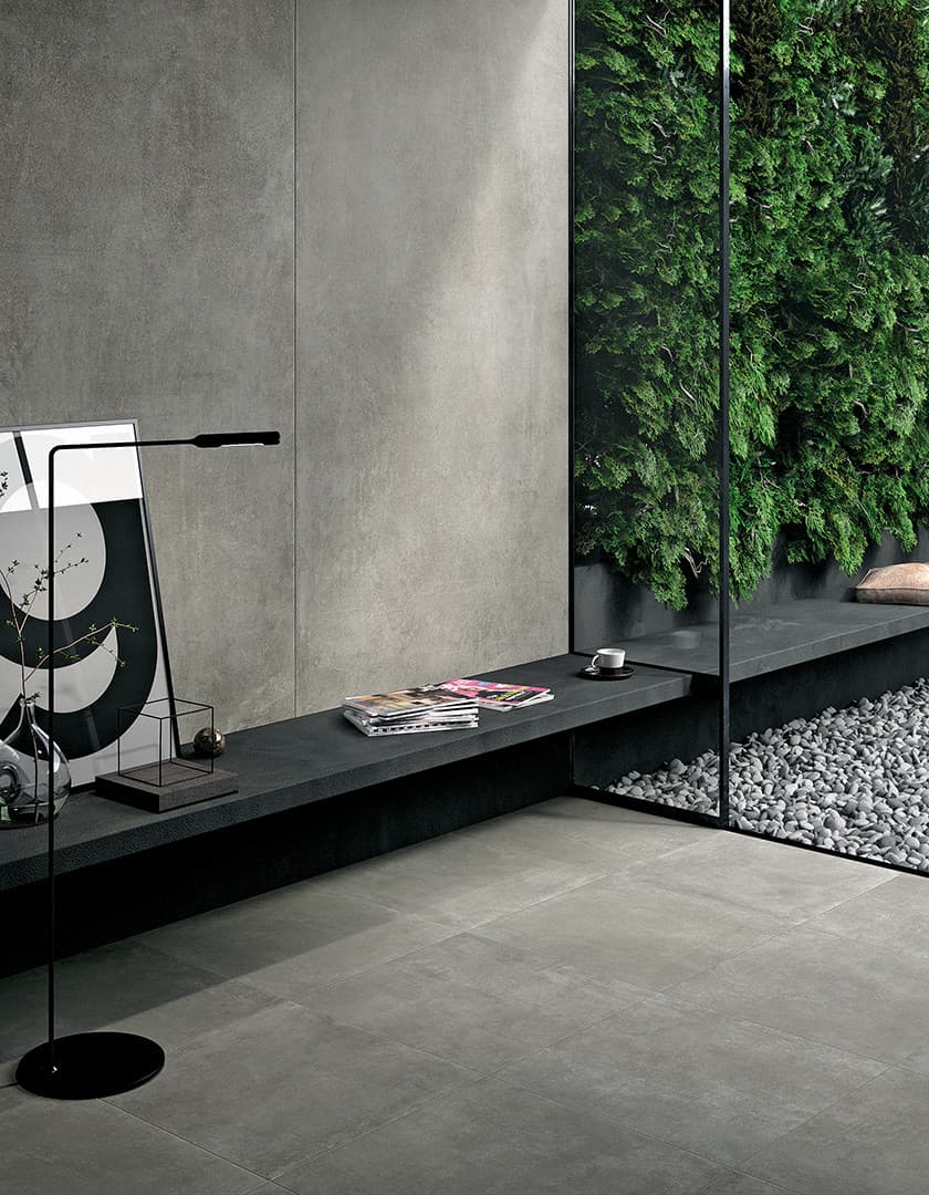 Carrelage finition pierre gris uni 60x60 cm dans un salon moderne gris notes de vert mur végétal étagère décorative et lampadaire design
