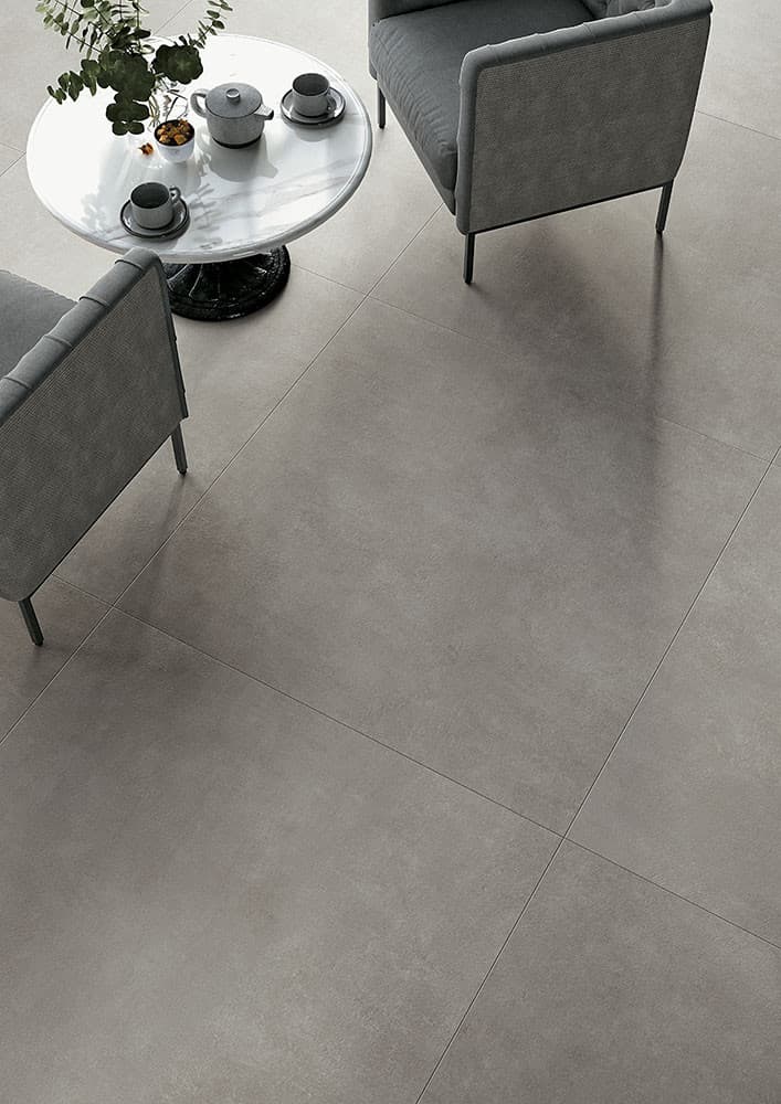 Carrelage effet pierre gris uniforme 60x60 cm dans un salon moderne avec mobilier gris et table blanche