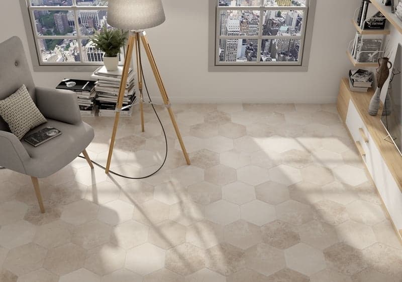 Carrelage effet pierre beige hexagonal dans un salon moderne aux murs gris, mobilier en bois clair et accents décoratifs taupe