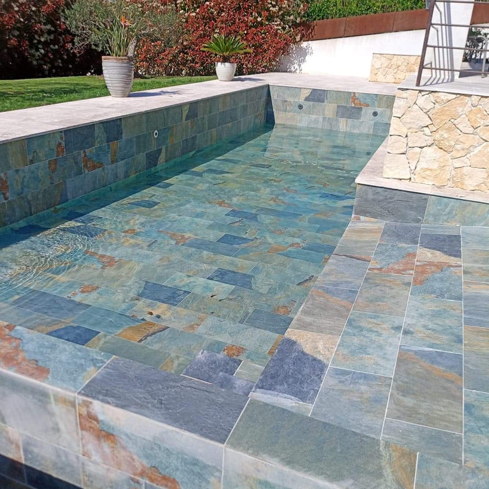 Carrelage pierre multicouleur 30x60 cm dans une piscine extérieure avec des tons bleus et verdâtres sur les murs et sol