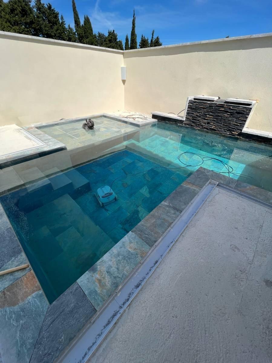 Carrelage pierre multicouleur 30x60 cm dans une piscine extérieure sur fond beige avec robot de nettoyage