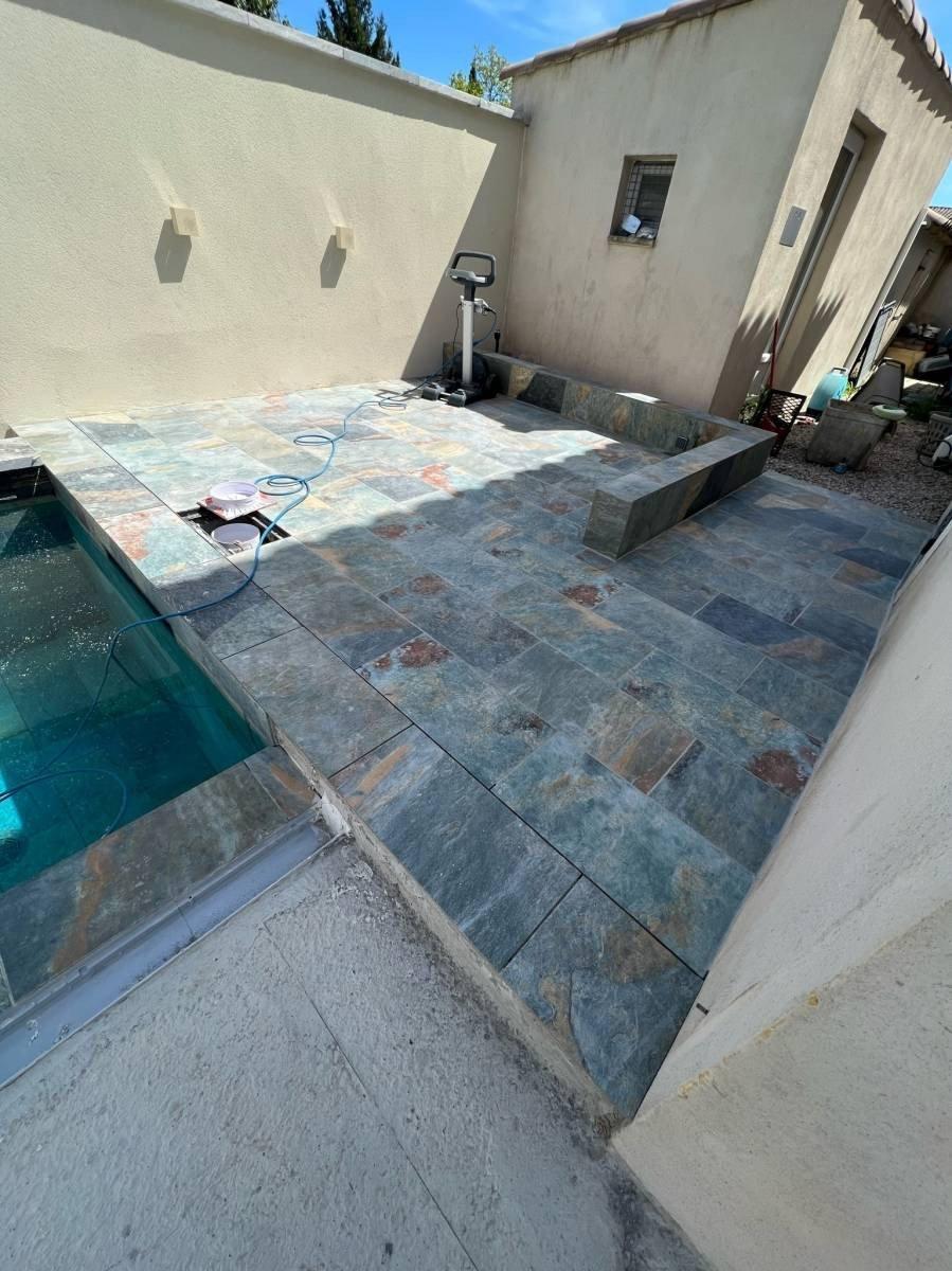 Carrelage pierre multicouleur avec nuances de bleu et de rouille 30x60 cm sur une terrasse extérieure beige avec piscine et équipement dentraînement