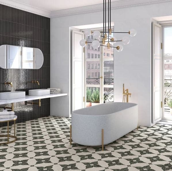 Carrelage Terrazzo noir et blanc dans une salle de bain élégante avec baignoire ovale et robinetterie dorée sur fond de murs gris et noirs