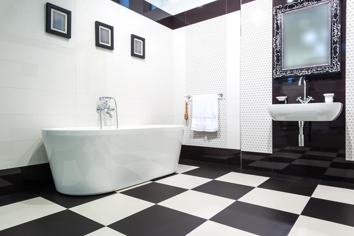 Carrelage uni noir et blanc dans une salle de bains moderne avec baignoire blanche, murs carrelés et lavabo