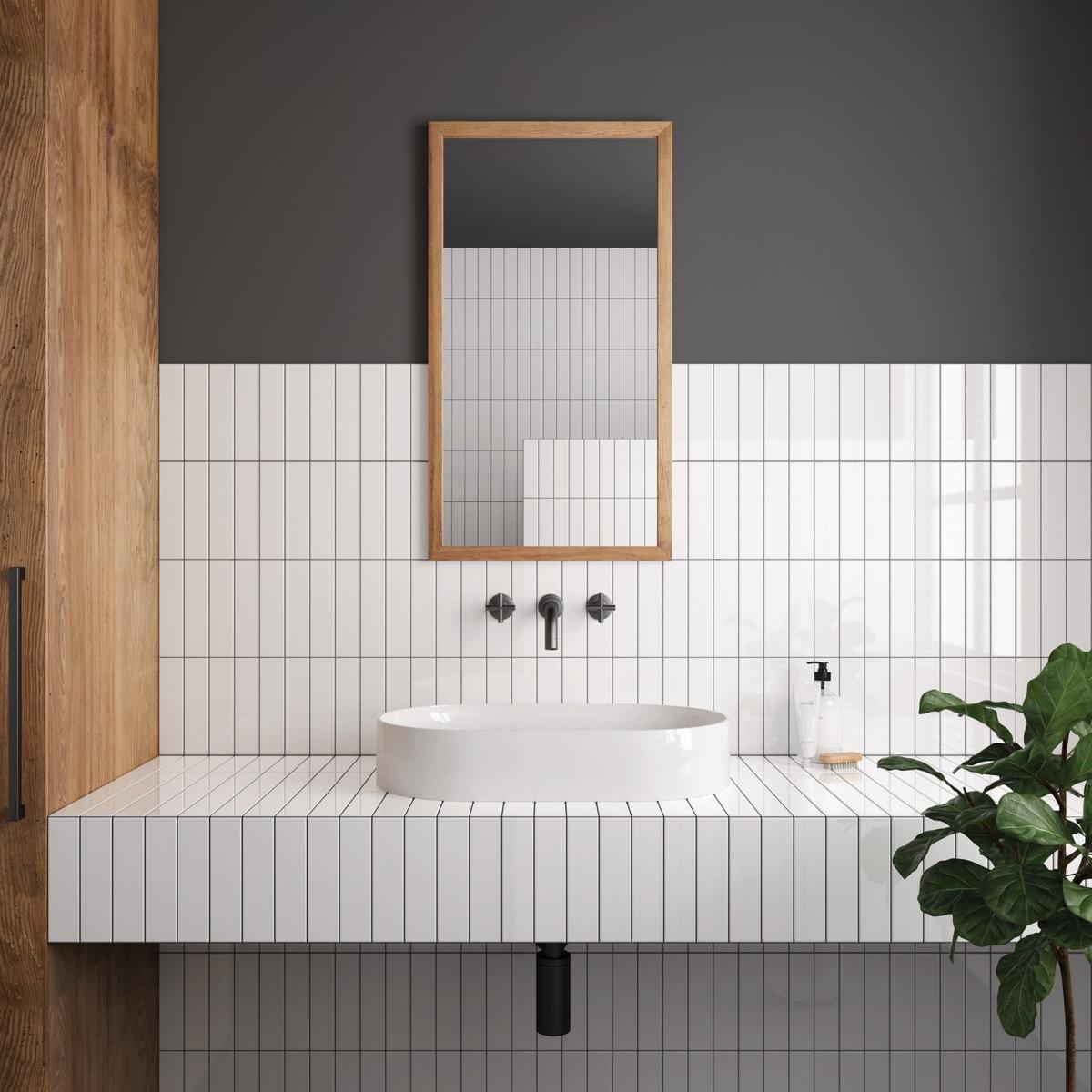 Carrelage uni blanc dans une salle de bain épurée avec murs gris, lavabo moderne, miroir en bois et plante verte