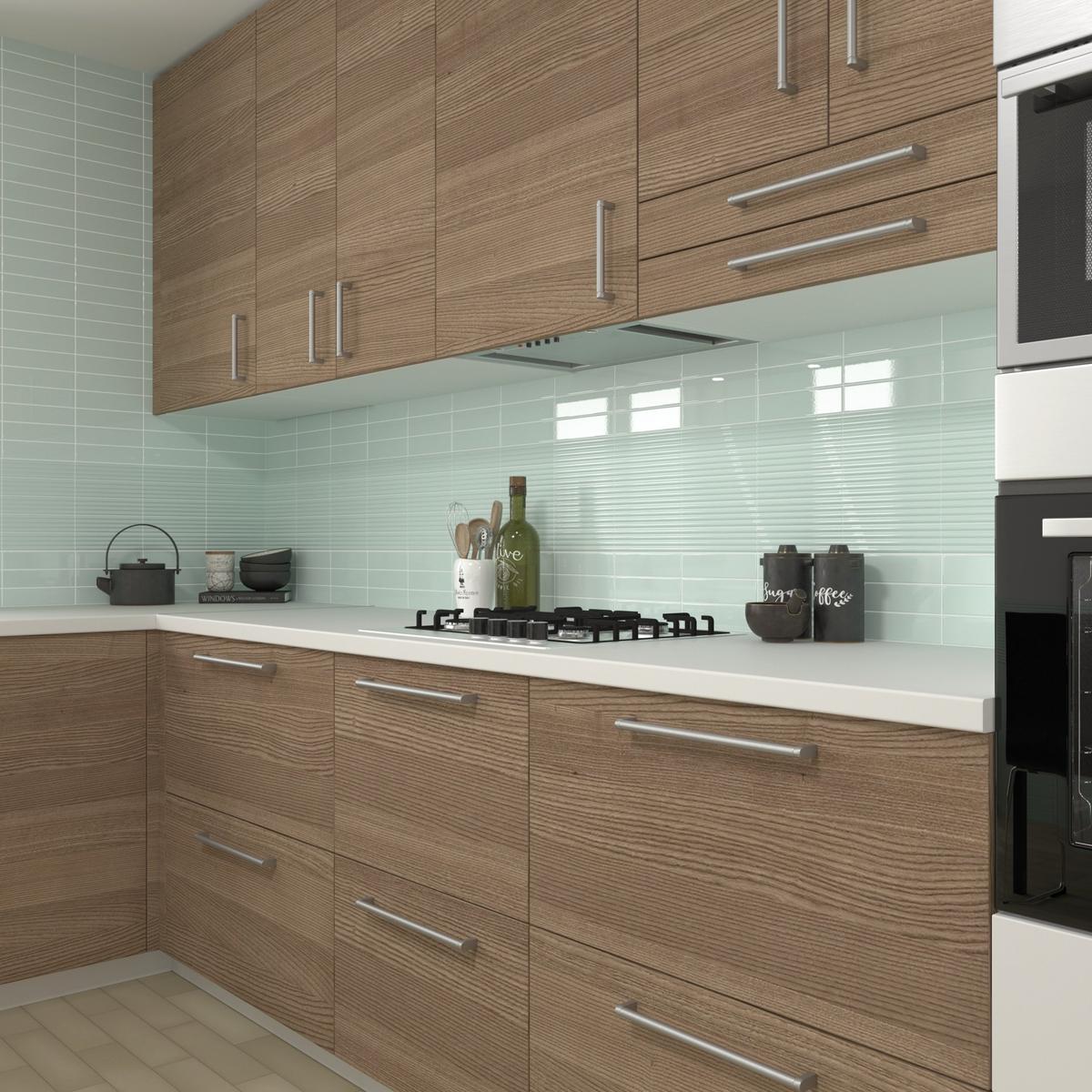 Carrelage uni vert clair dans une cuisine avec meubles en bois marron, plan de travail blanc, éléments décoratifs verts et noirs