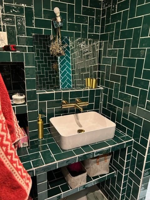 Carrelage uni vert 7,5x15 cm dans une salle de bain tons sur tons, accessoires dorés, sanitaires blancs