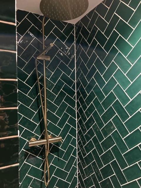 Carrelage uni vert émeraude 7,5x15 cm dans une salle de bain moderne avec des accents de métal chrome et une robinetterie élégante