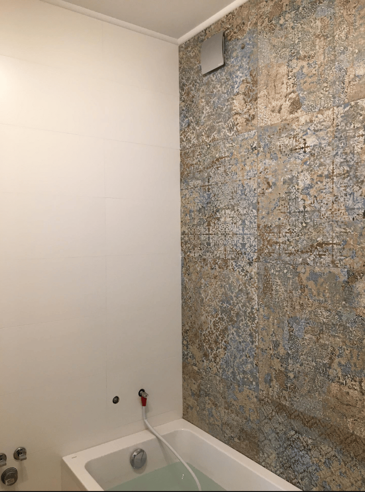 Carrelage effet tissu beige aux motifs floraux 50x100 cm dans une salle de bain aux murs blancs avec baignoire remplie