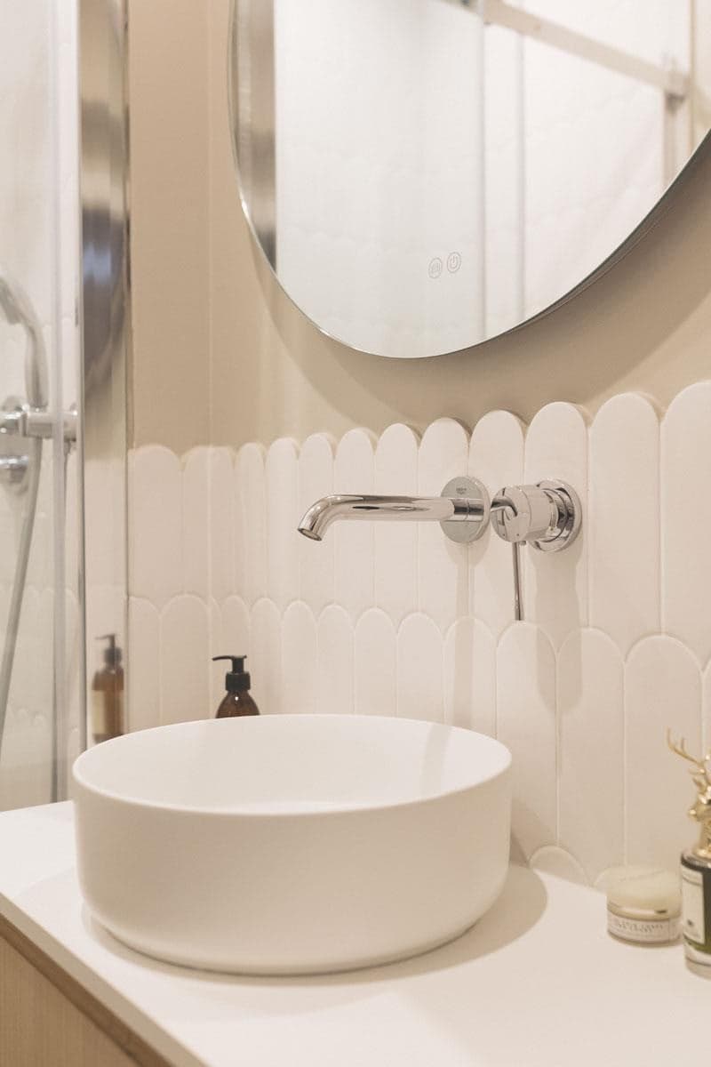 Carrelage mural uni blanc à texture ondulée 7,2X19,5 dans une salle de bain beige avec vasque ronde et miroir