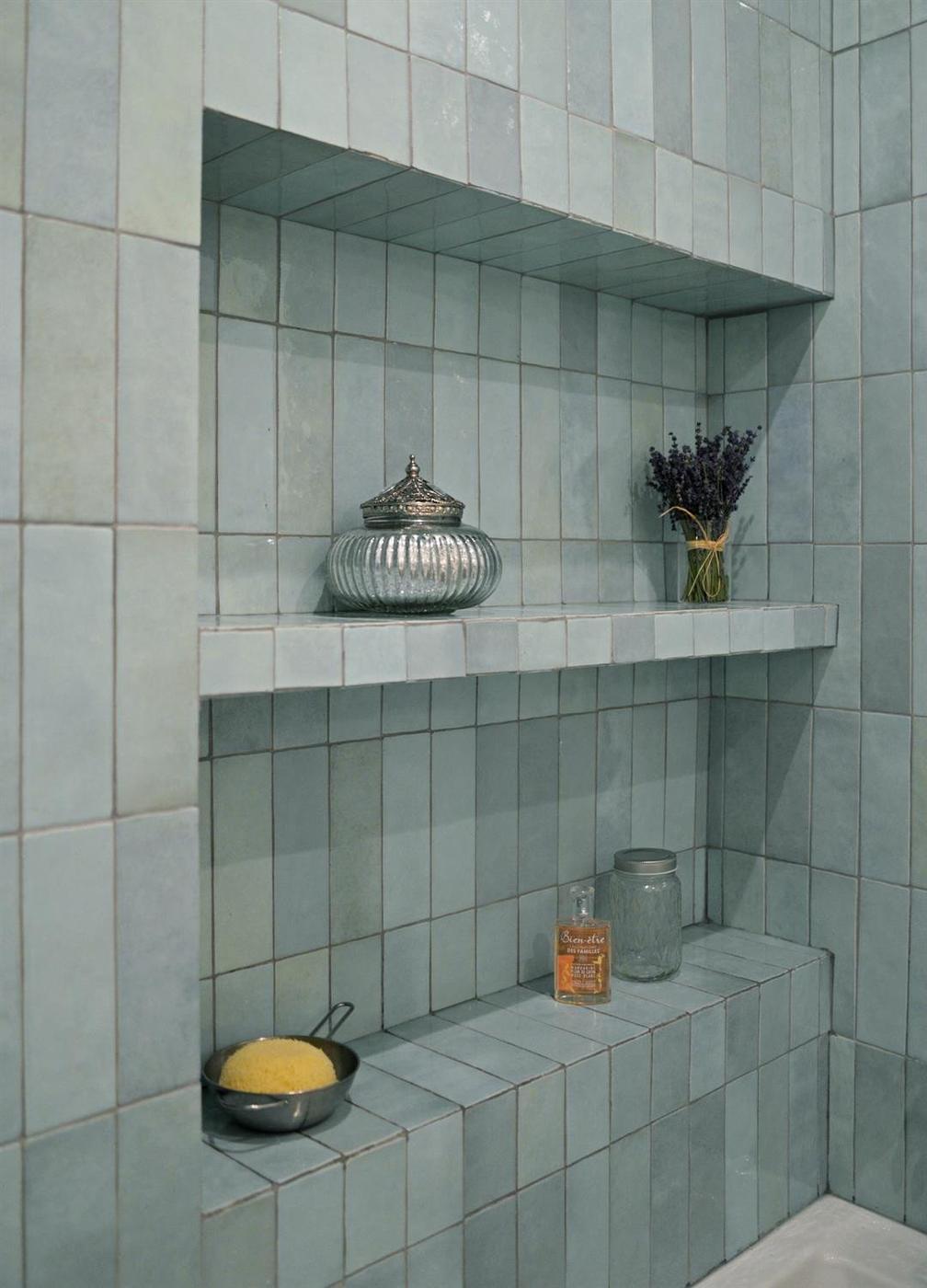 Zellige bleu ciel lisse 6,5X20 dans une salle de bain tons gris accueillant des accessoires décoratifs et de bain
