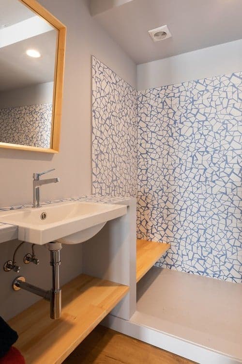 Carrelage Terrazzo blanc avec motifs bleus 30x30 cm dans une salle de bain épurée sur des éléments en bois clair et des accents de gris