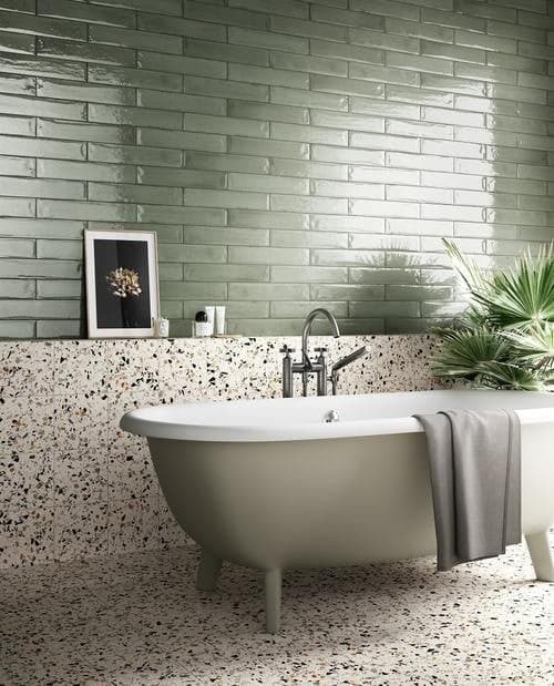 Carrelage uni vert 7,5X40 dans une salle de bain beige avec sol terrazzo blanc, baignoire et plantes vertes