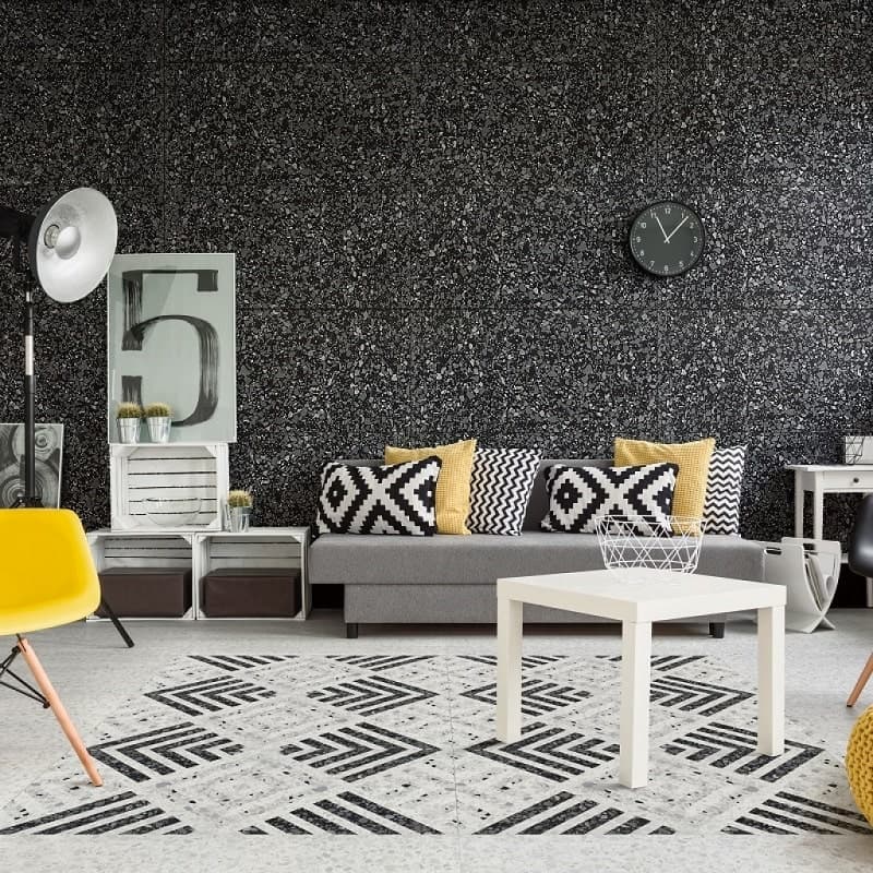 Carrelage Terrazzo blanc et noir 60x60 cm dans un salon moderne aux meubles gris et jaunes avec murs noirs et blancs
