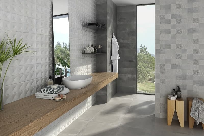 Carrelage effet béton gris motifs géométriques 60x60 cm dans une salle de bain épurée blanche avec meuble en bois et vue sur la nature
