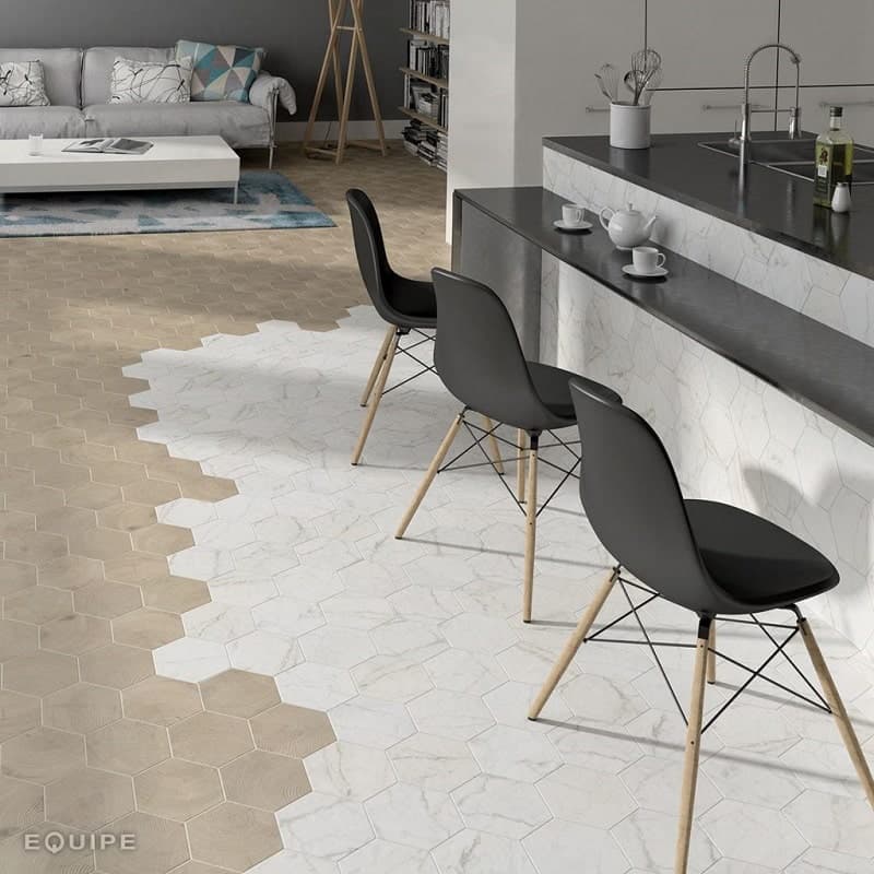 Carrelage marbre blanc hexagonal sur un sol dun salon avec canapé gris, table basse et éléments de cuisine noirs