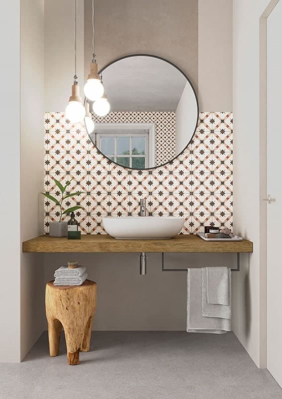 Carreau de ciment rouge avec motifs noir et blanc 30x30 cm dans une salle de bain aux murs beiges et étagère en bois avec lavabo, miroir et éclairage suspendu