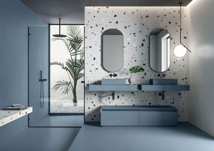 Carrelage Terrazzo blanc avec éclats multicolores 80x80 cm dans salle de bain moderne ton bleu mobilier assorti plante verte