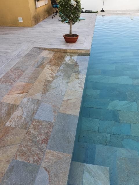 Carrelage effet pierre beige nuances de brun et gris 30x60 cm sur terrasse extérieure à côté dune piscine