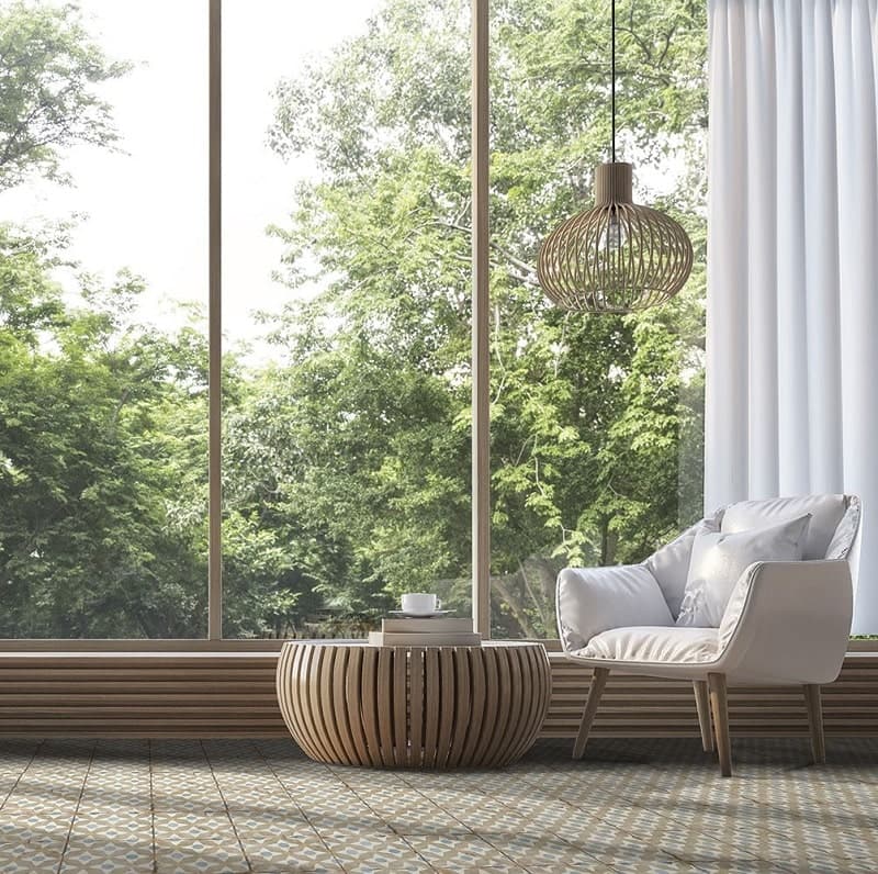 Carreau de ciment multicouleur motifs géométriques 20x20 cm sur sol de salon nuances de blanc fauteuil beige table ronde bois luminaire suspendu