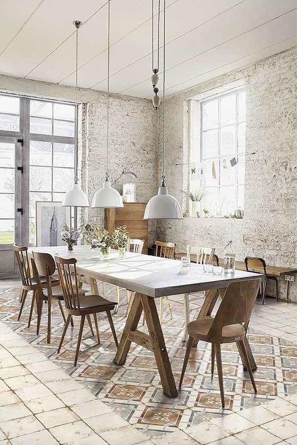 Carreau de ciment blanc avec motifs géométriques dans une salle à manger aux murs en briques, mobilier en bois naturel
