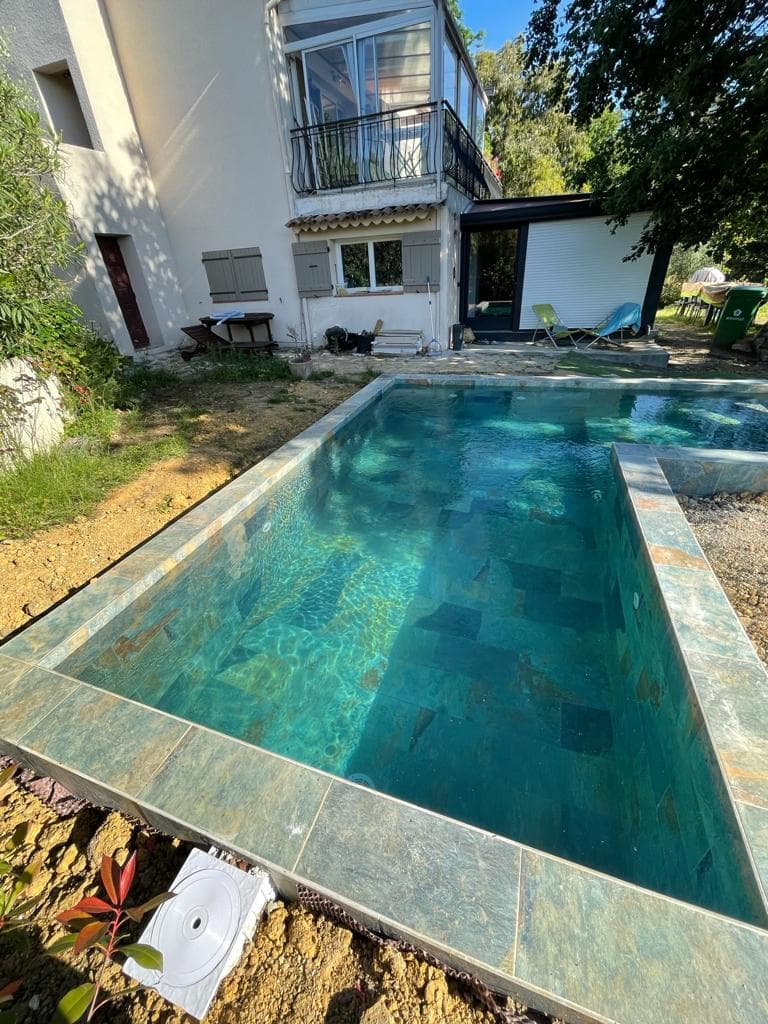 Carrelage pierre multicouleur 30x60 cm dans une piscine extérieure entourée de verdure