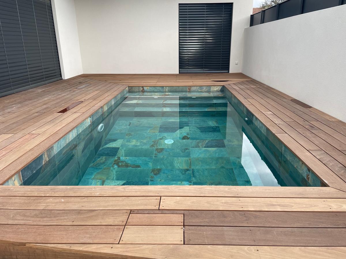 Carrelage aspect pierre multicouleur sans motifs 30x60 cm sur bord de piscine avec terrasse en bois brun clair