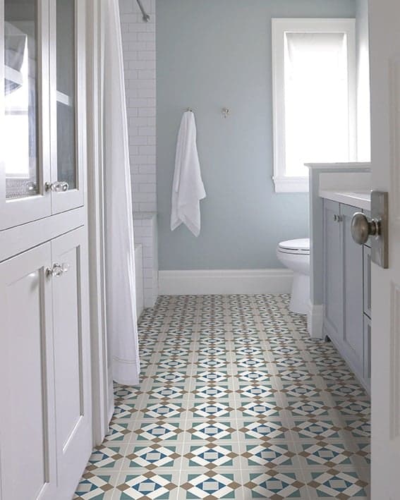 Carreau de ciment vert avec motifs géométriques bleu et beige 20x20 cm dans une salle de bain blanche avec des éléments en bois clair