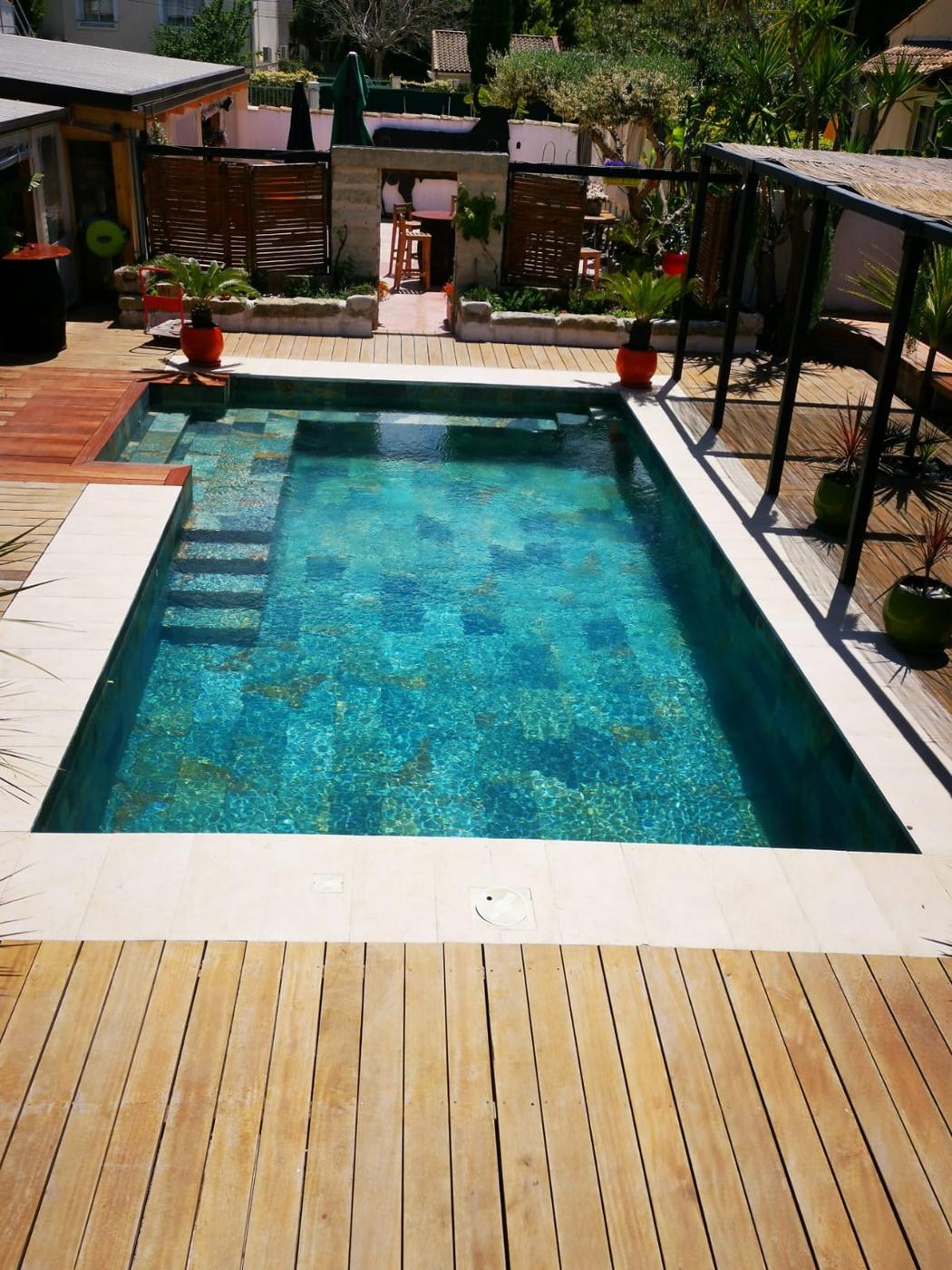 Carrelage aspect pierre multicouleur 30x60 cm sur une terrasse bois tropical avec piscine et végétation environnante
