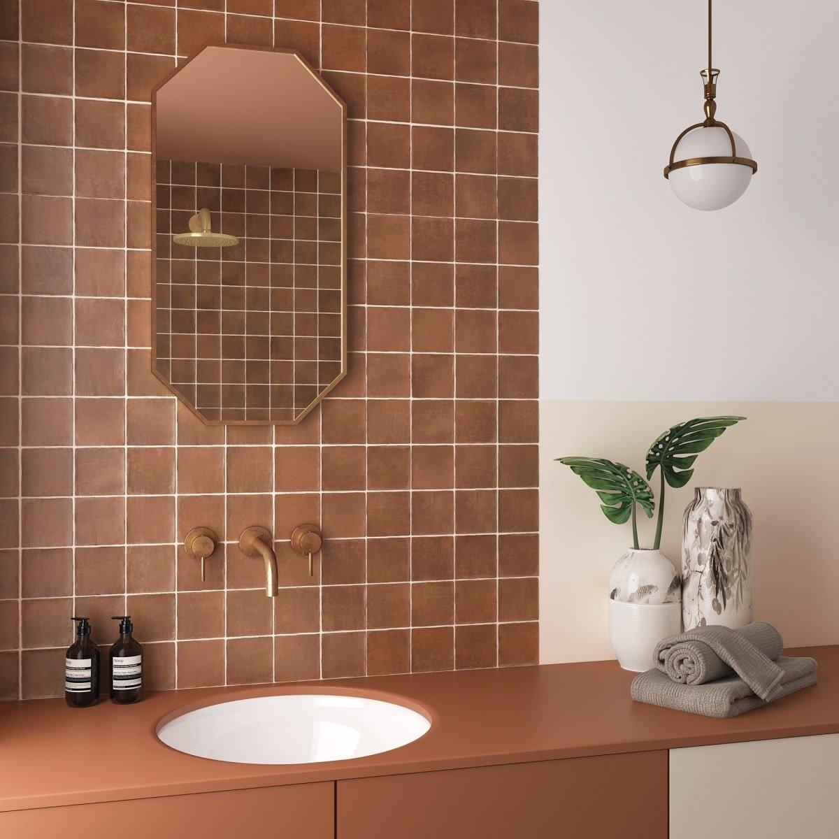 Zellige rouge brillant 10x10 cm sur le mur de la salle de bain tons neutres avec vasque, miroir et luminaire suspendu