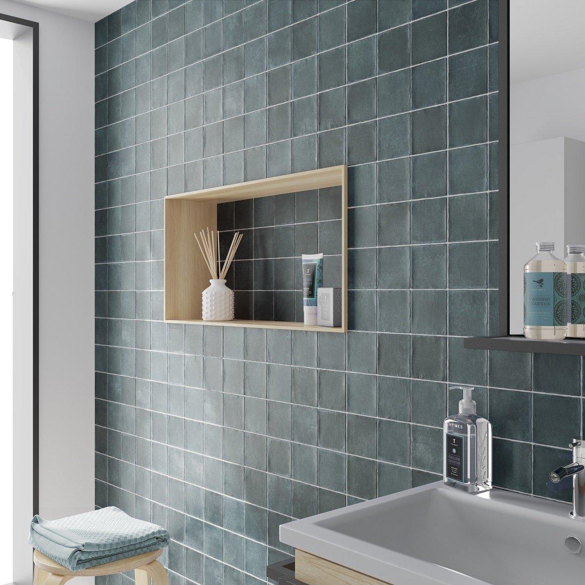 Carrelage Zellige bleu nuances dazur sans motifs 10x10 cm dans une salle de bain aux murs blancs avec étagère et accessoires de bain