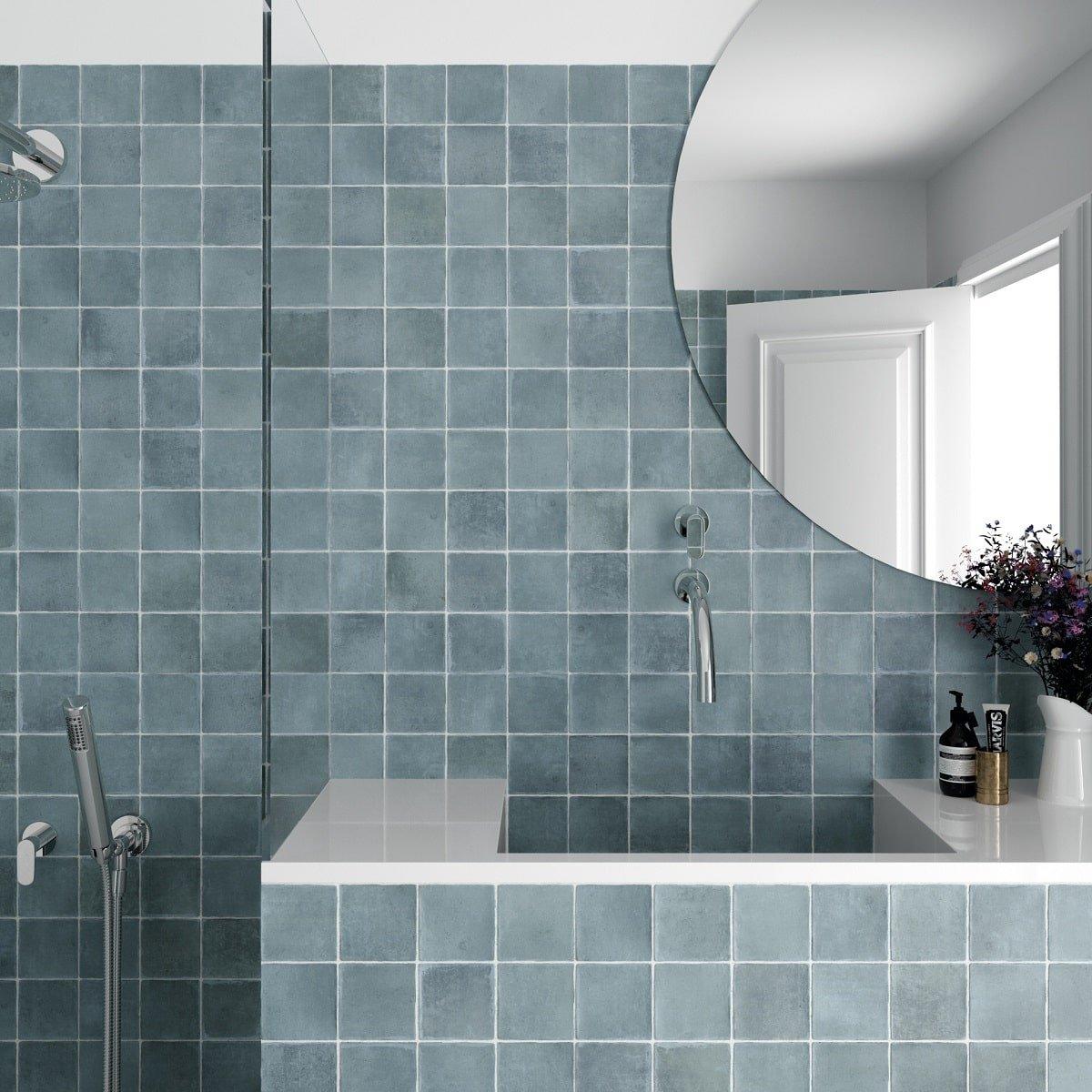 Zellige carrelage bleu dégradé 10x10 cm dans une salle de bain blanche avec douche et accessoires en chrome