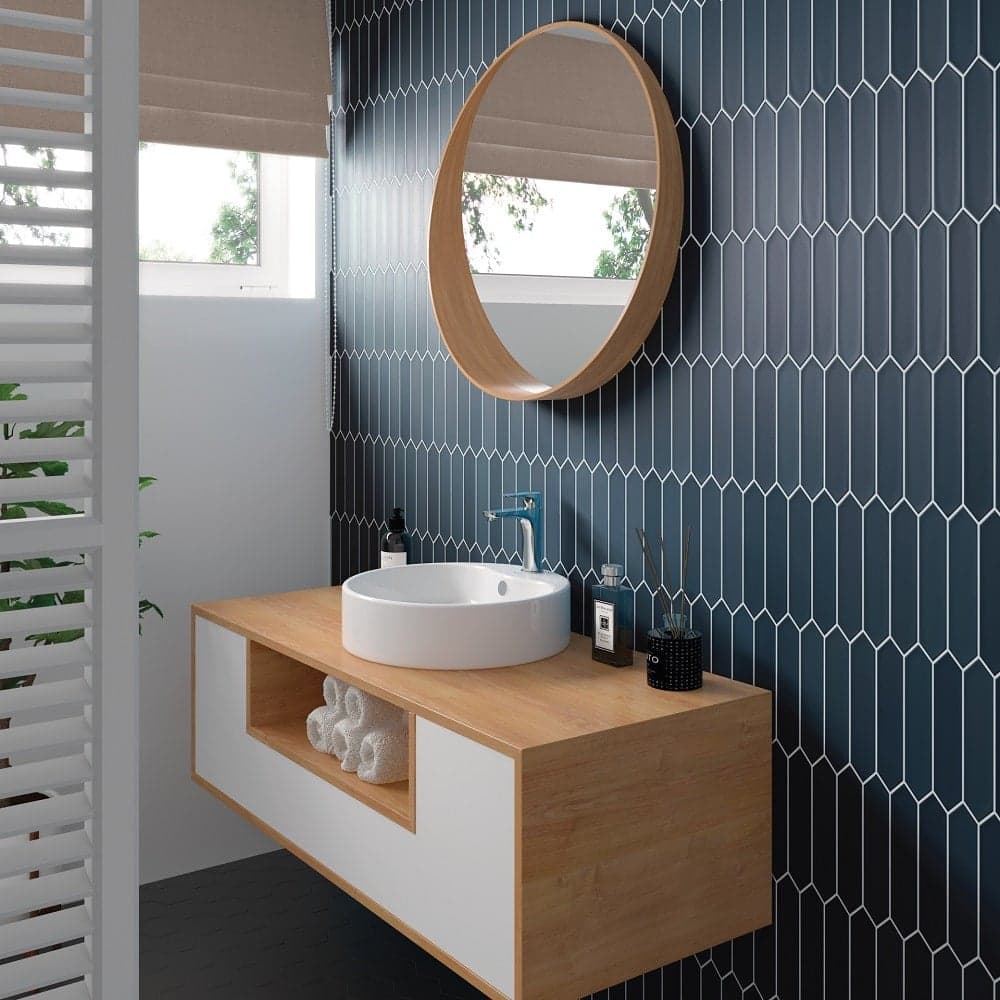 Carrelage uni bleu foncé 5X25 dans salle de bain moderne sur meuble en bois clair, blanc, avec miroir rond et lavabo blanc, plante verte