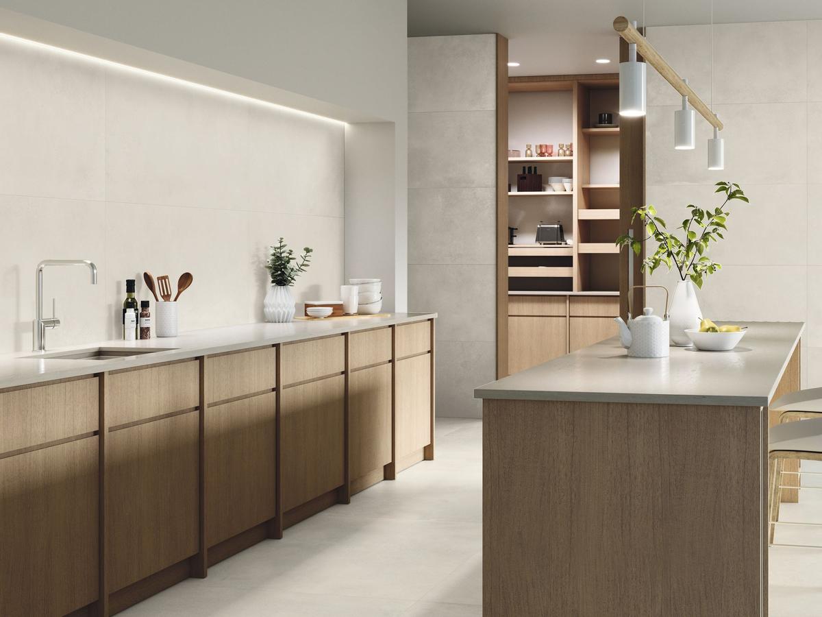 Carrelage effet béton beige lisse 60x120 cm sur une cuisine moderne aux tons bois clair avec îlot central et étagères intégrées