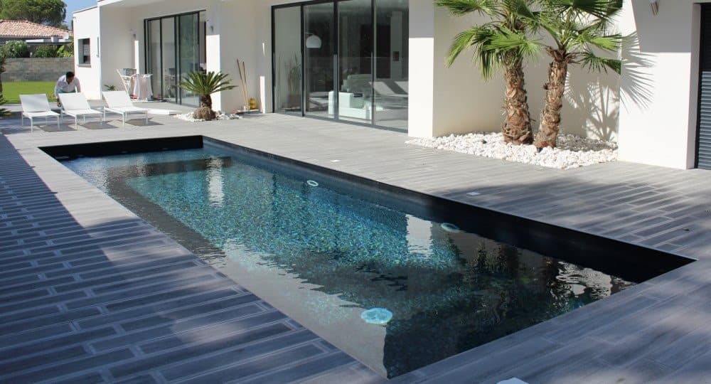 Carrelage uni noir 30x30 cm dans un espace extérieur avec piscine, meubles blancs, palmiers et maison moderne en arrière-plan